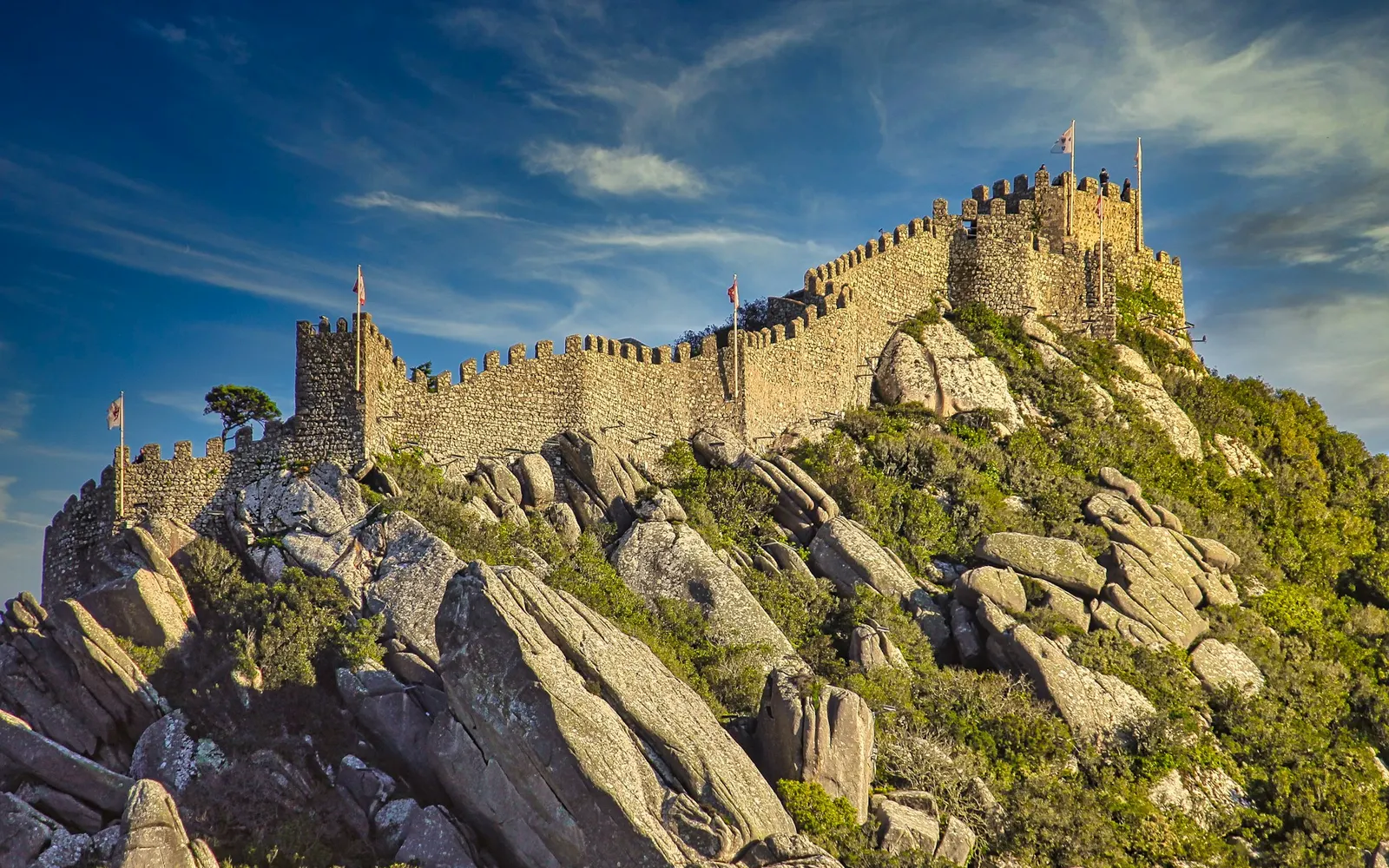 Golden stone battlements of the Castelo dos Mouros built directly onto granite outcrops