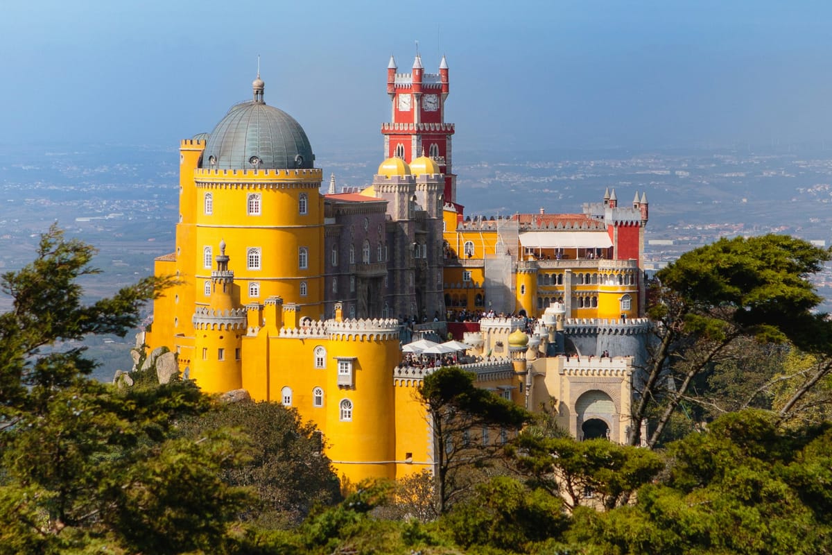 The battlements of the Castelo dos Mouros wrapping the Sintra mountain ridge, with Pena Palace visible on the adjacent peak